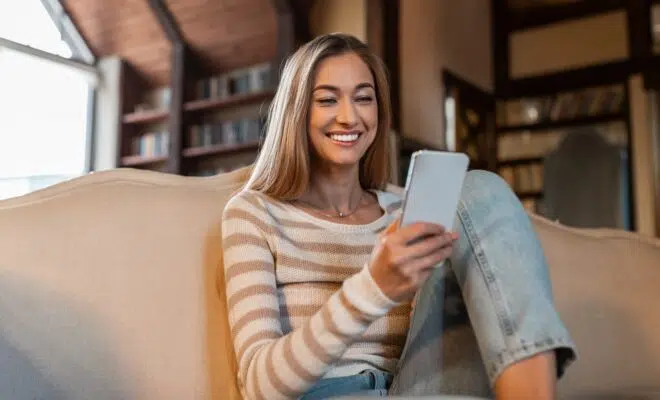 Portrait of smiling woman using smartphone at home