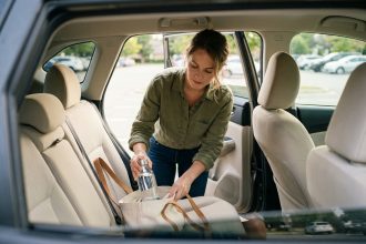 Femme plaçant soigneusement une bouteille d'eau hermétique dans un sac réutilisable sur la banquette arrière d'un SUV